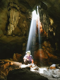 Man sitting on rock formation in cave