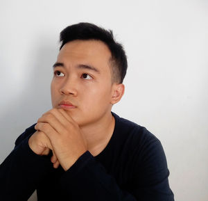 Portrait of young man looking away against white background