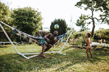 Son looking at father playing with ball in yard