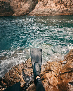 Low section of person on rock by sea