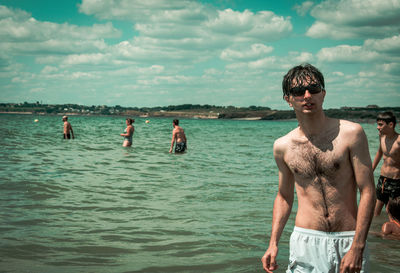 Men standing on beach against sky