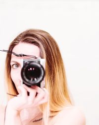 Portrait of woman photographing against white background