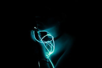 Midsection of woman holding illuminated string light against black background