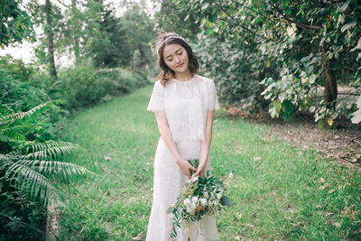 Bride with bouquet standing on grassy field