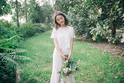 Portrait of young woman standing against tree