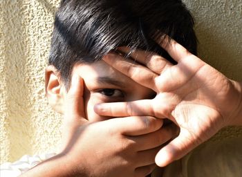 Close-up portrait of woman covering face with hands