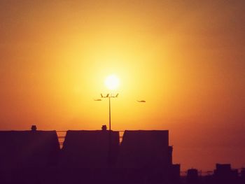 Low angle view of silhouette buildings against orange sky