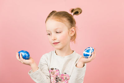 Portrait of cute girl holding globe against pink background