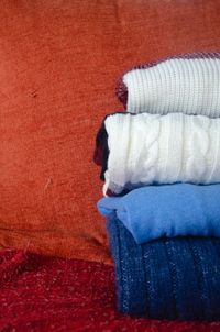 Pile of woolen sweaters on sofa