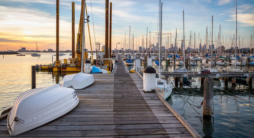 Boats moored at harbor against sky during sunset