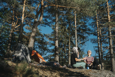 Two senior women sitting near tent at campsite