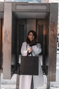 Portrait of woman holding bag standing outdoors
