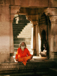 Woman sitting on staircase outside building