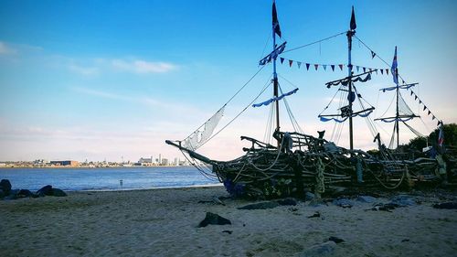 Sailboats moored on beach against sky