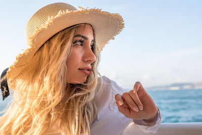 Close-up of thoughtful young woman wearing hat against sky
