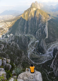 Rear view of man sitting against mountains