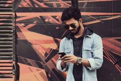 Young man using mobile phone while standing outdoors