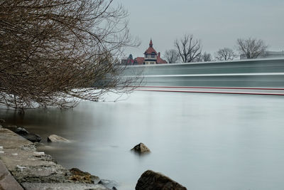 Scenic view of river by building against sky during winter