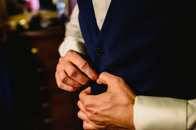 Midsection of bridegroom getting dressed