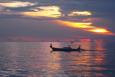 Boat sailing in sea at sunset