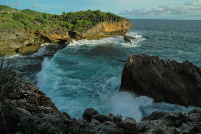 Scenic view of rocks in sea against sky