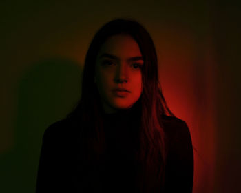 Portrait of beautiful young woman standing in darkroom