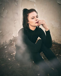 Young woman looking away while sitting outdoors