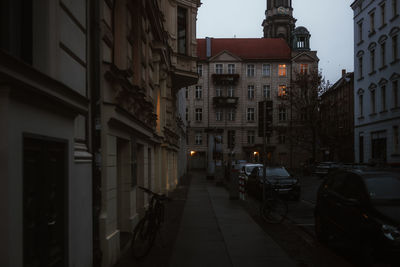 Street amidst buildings in city at dusk