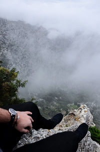 Midsection of man on rock against mountains