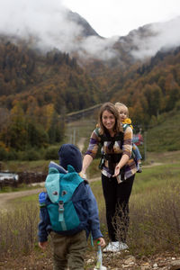 Full length of happy friends sitting on mountain against mountains