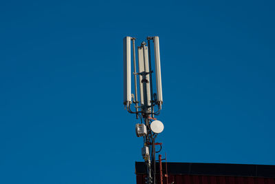 Low angle view of communications tower against clear blue sky