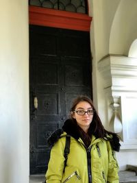 Portrait of young woman standing against wall