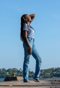 Full length of woman standing against blue sky