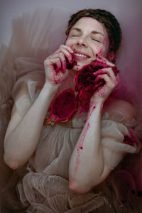 Smiling woman with pitaya in her hands lying in water