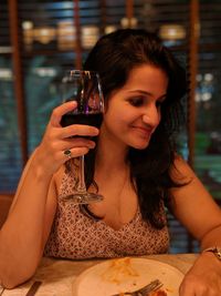 Portrait of a young woman drinking glass at restaurant