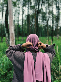 Rear view of woman standing in forest