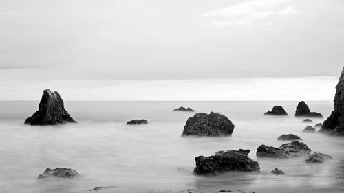 Rocks in sea against sky