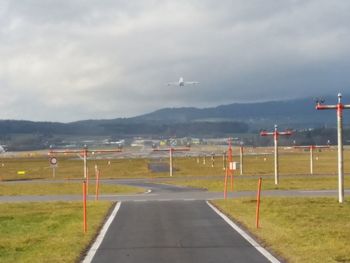Road leading towards mountain against cloudy sky