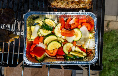 Tray with vegetables on the grill, standing on the backyard garden on the paving stone.