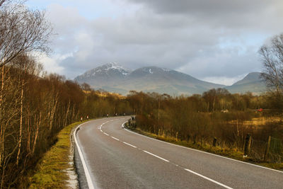 Road by mountains against sky