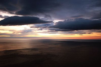Scenic view of sea against dramatic sky during sunset
