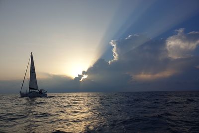 Sailboat sailing on sea against sky during sunset