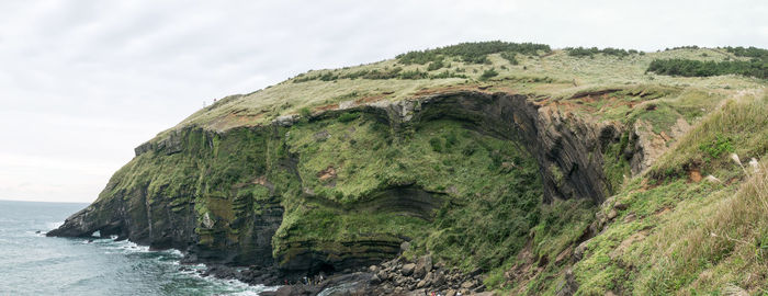 Scenic view of cliff by sea against sky