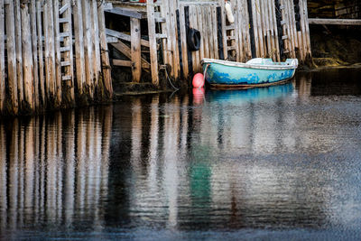 Boat moored by fence at lake