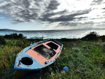 Abandoned boat in sea against sky