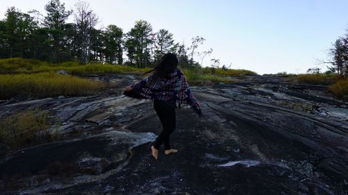 Rear view of woman walking on field against sky