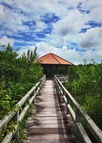 Wooden footbridge against cloudy sky
