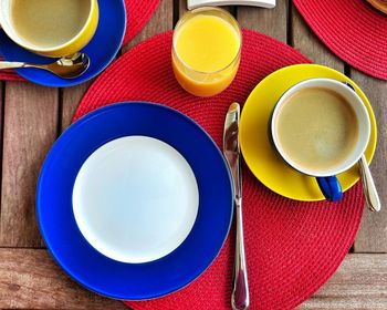 Directly above shot of empty plate by coffee and orange juice on table