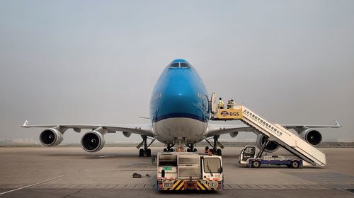 Airplane on airport runway against sky