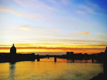 Silhouette bridge over river against sky during sunset